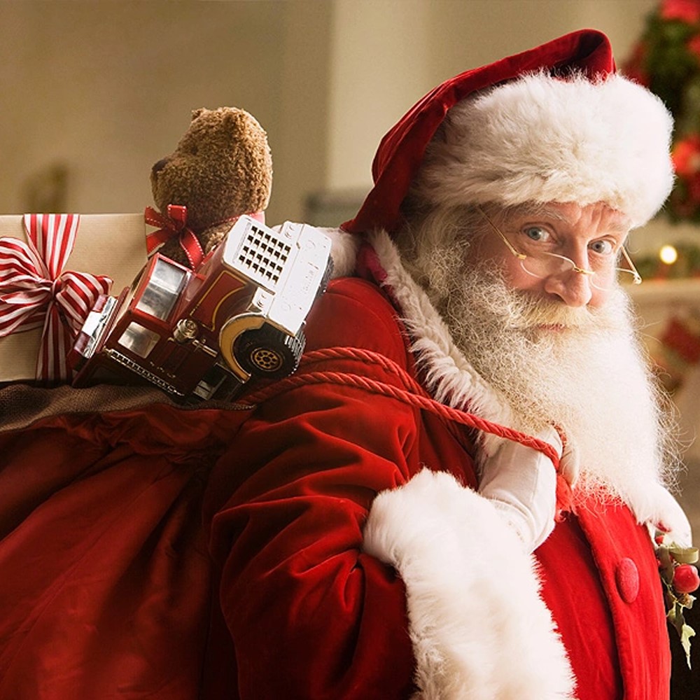 Mikołaj w stroju niosący worek prezentów.